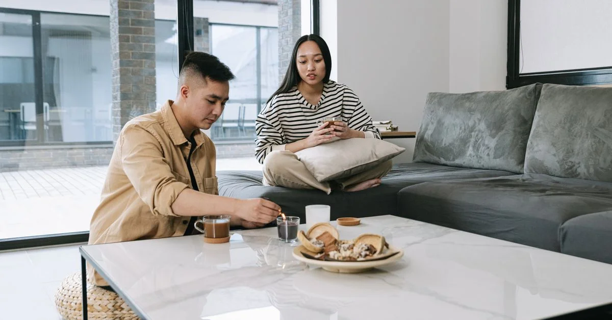 Couple asiatique se relaxant dans un salon moderne avec des bougies et des collations. Style Japandi.