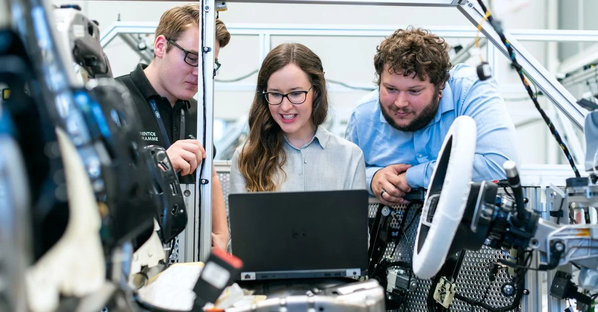 Ingénieurs collaborant sur un projet de voiture dans un atelier automobile moderne utilisant une technologie avancée.