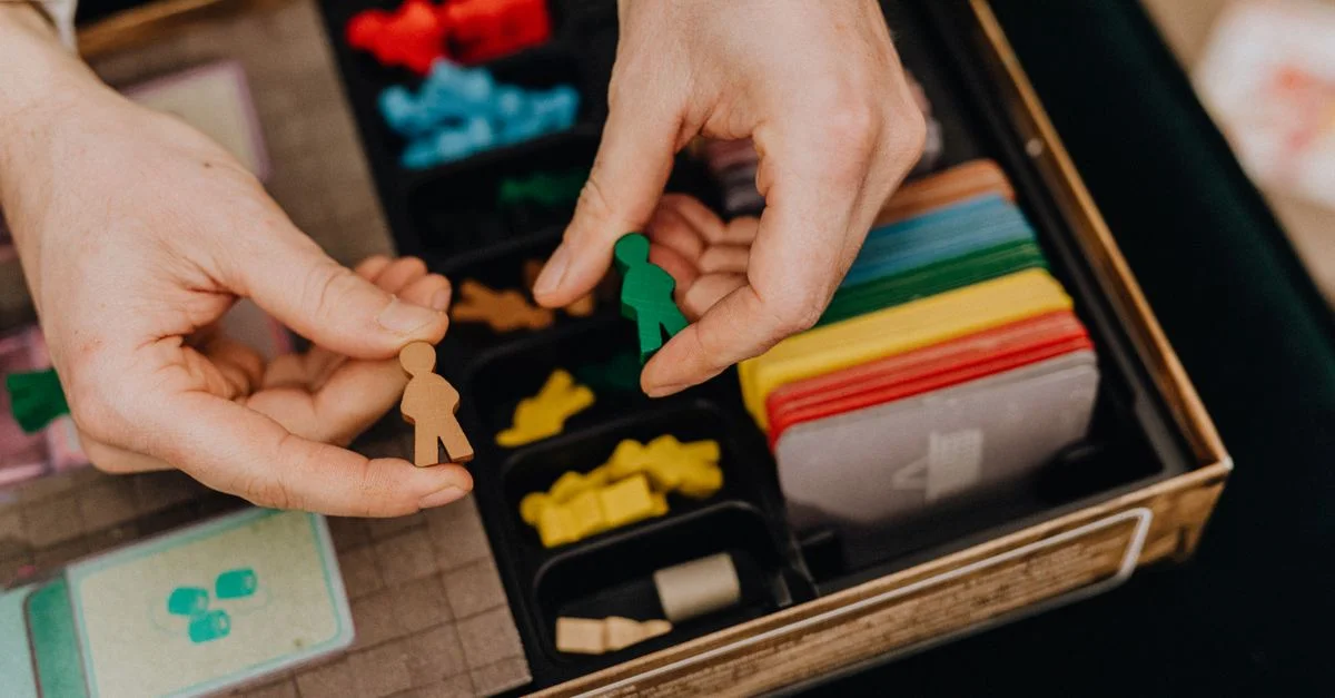 Mains arrangeant des pièces de jeu colorées pour un jeu de société. Favorise les loisirs et les moments de plaisir en famille.