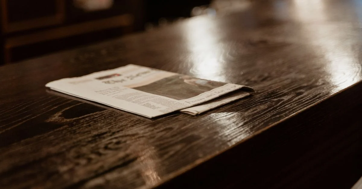 Une prise de vue en nature morte d'un journal reposant sur une table en bois poli dans un cadre intérieur confortable.