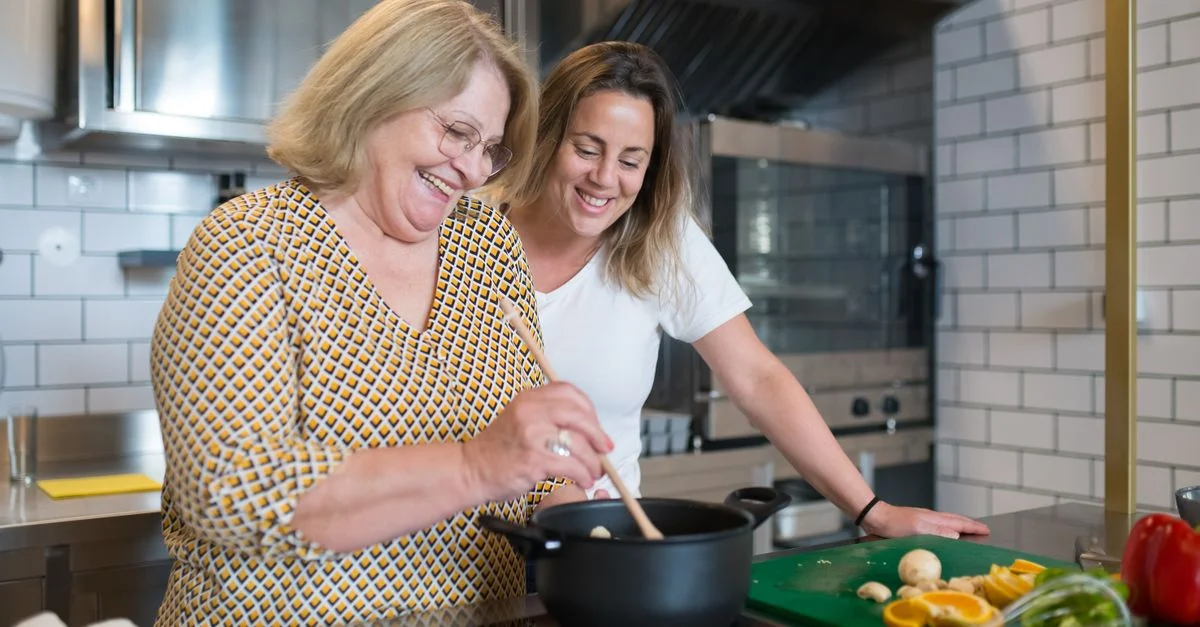 Une mère et sa fille joyeuses partageant un moment de cuisine dans une cuisine moderne.