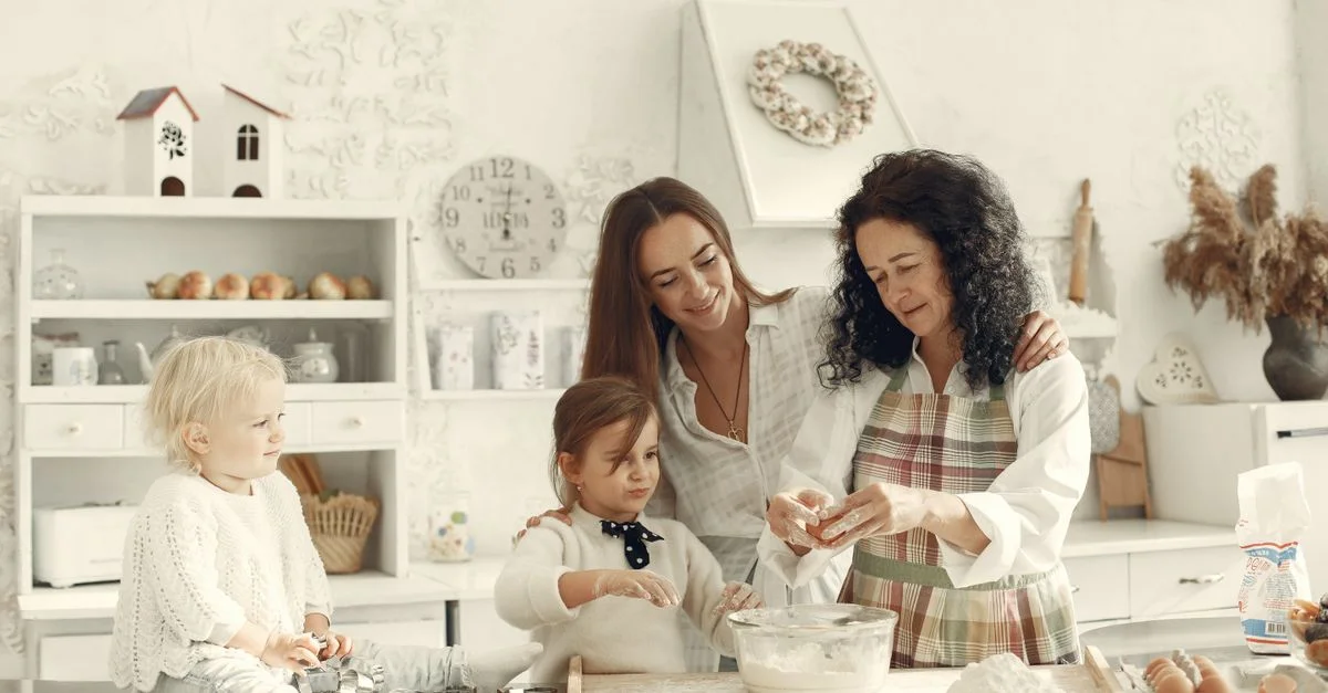 Une grand-mère, une mère et des enfants cuisinant ensemble dans une cuisine lumineuse, profitant du lien familial.