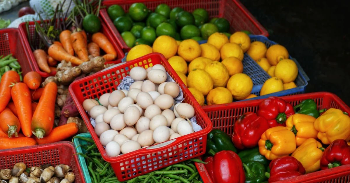 Fruits et légumes colorés exposés dans des paniers au marché en plein air.
