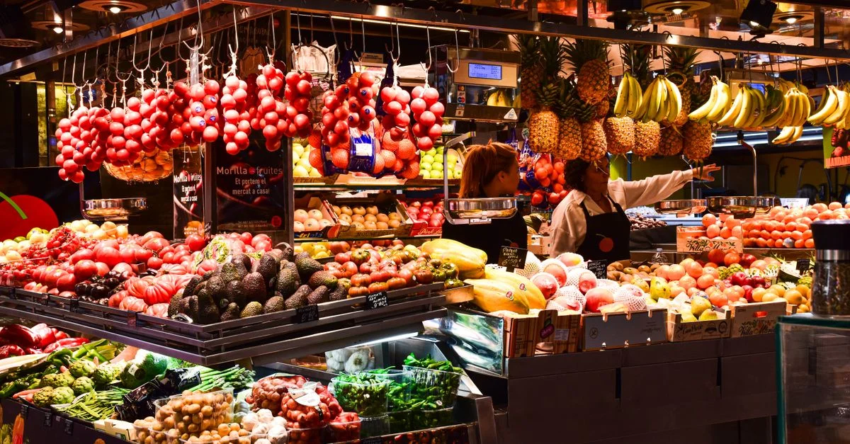 Stand de fruits colorés au marché de La Boqueria, Barcelone, présentant des produits frais sous des lumières chaudes.