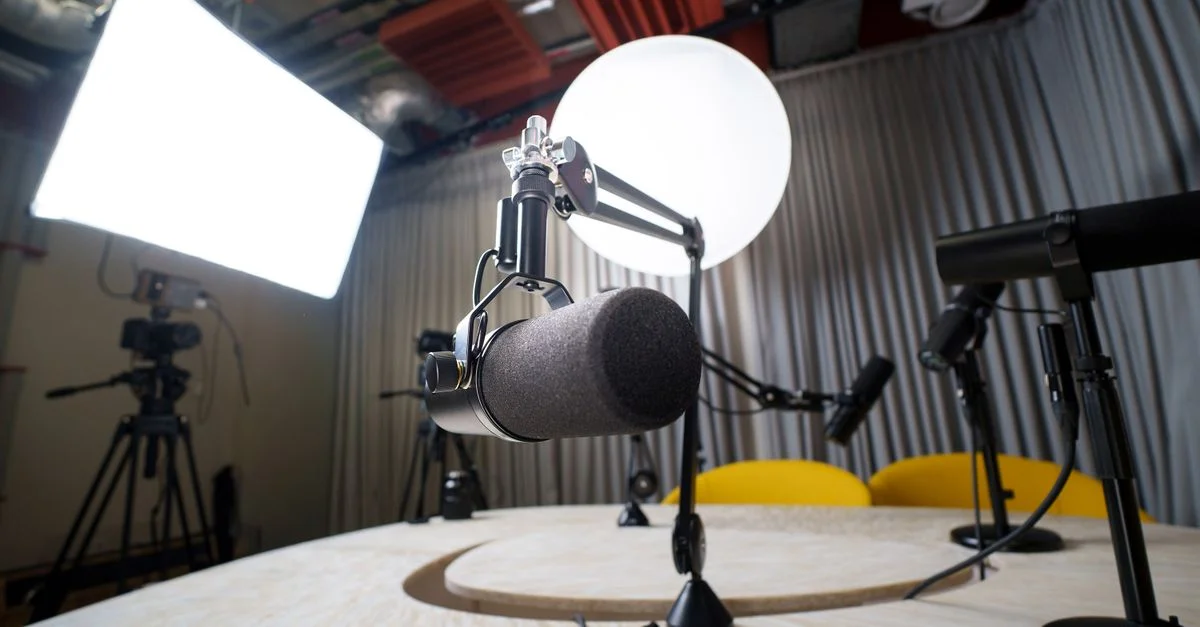 Un studio d'enregistrement de podcast moderne avec des microphones, des chaises et du matériel d'éclairage.