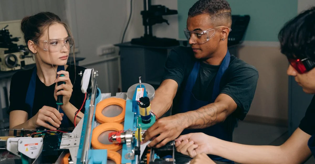 Trois ingénieurs collaborent sur des machines industrielles, mettant l'accent sur le travail d'équipe et la technologie dans un environnement de fabrication.