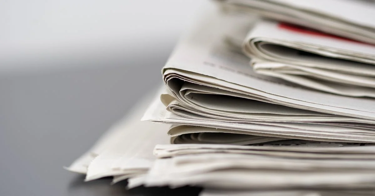 Gros plan de journaux empilés sur une table, représentant les médias et le journalisme.