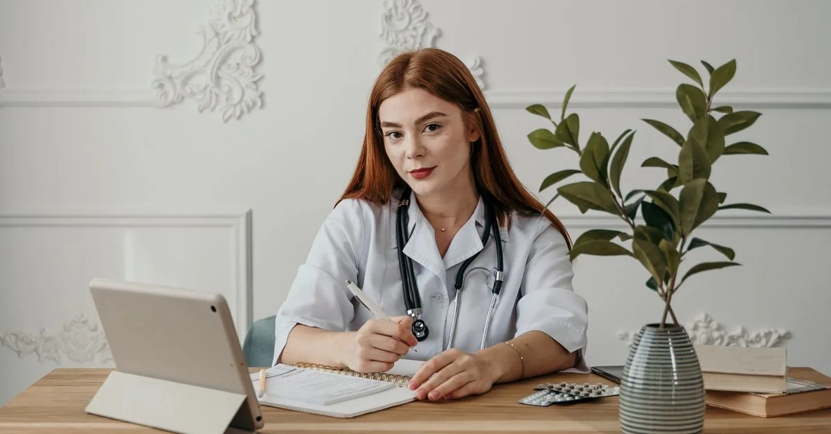 Jeune médecin écrivant des notes sur une tablette dans un bureau moderne.