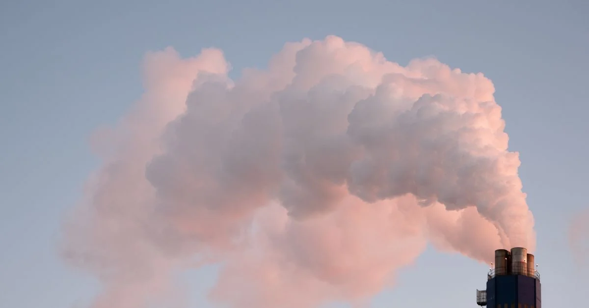 De la fumée s'élevant d'une cheminée industrielle contre un ciel dégagé, illustrant la pollution.